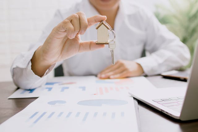 person holding key chain with a house on the end